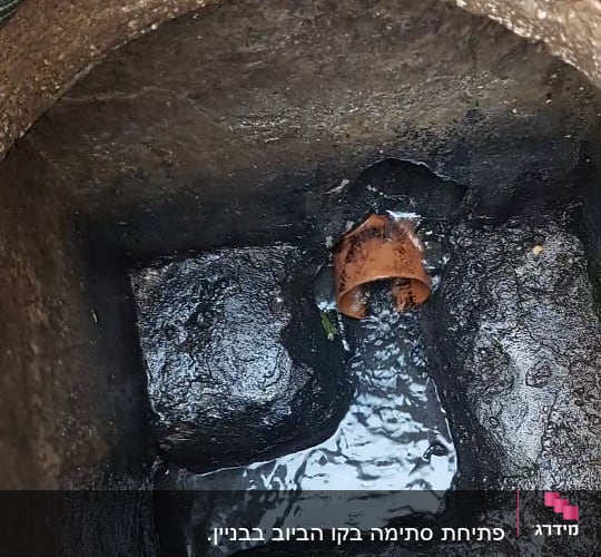 צינור ביוב עם מים זורמים בתוך בור